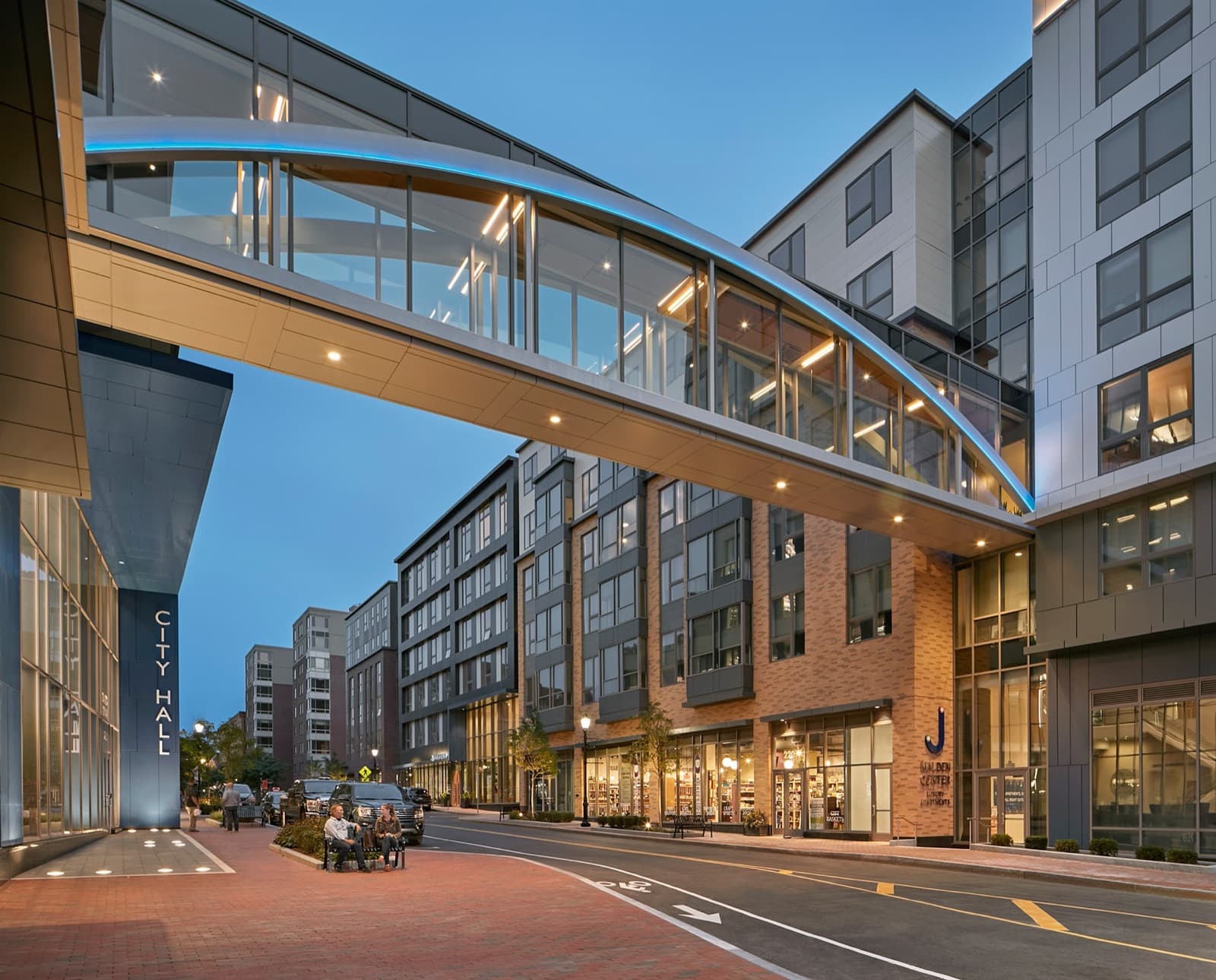Downtown Malden Center at dusk, with its lit glass skybridge